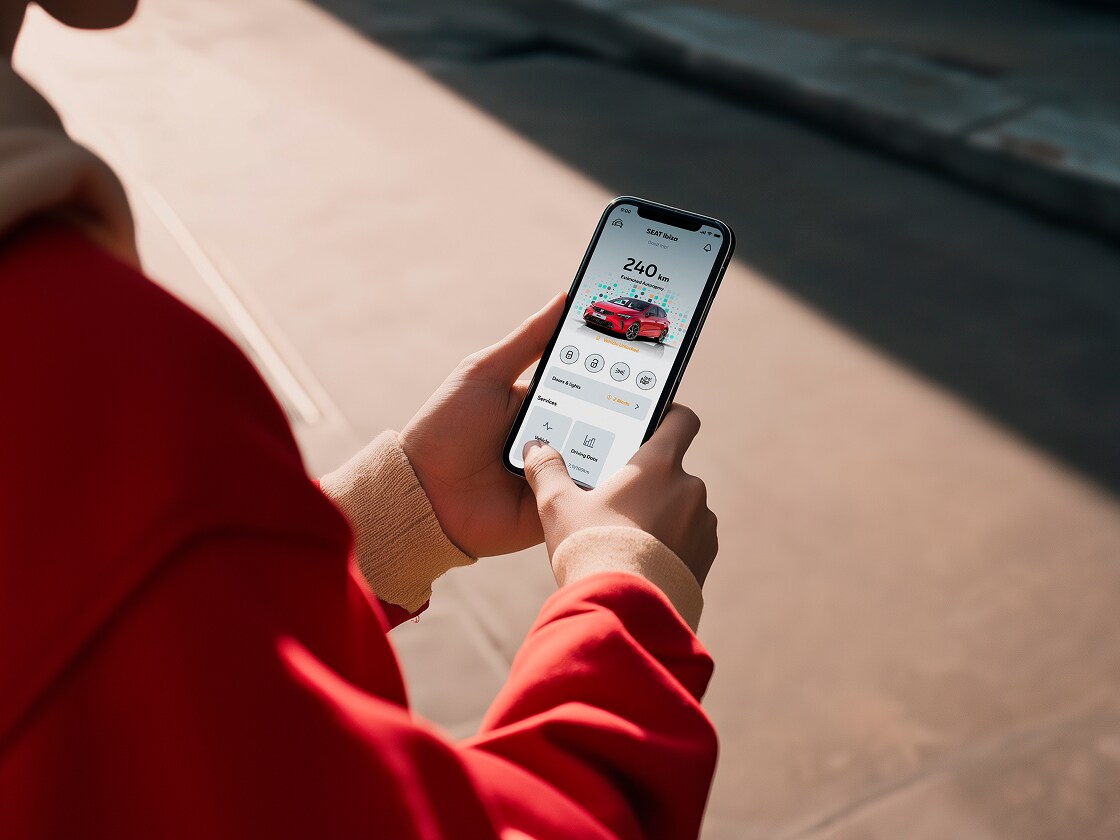 Personne tenant son smartphone et utilisant les fonctions à distance du siège