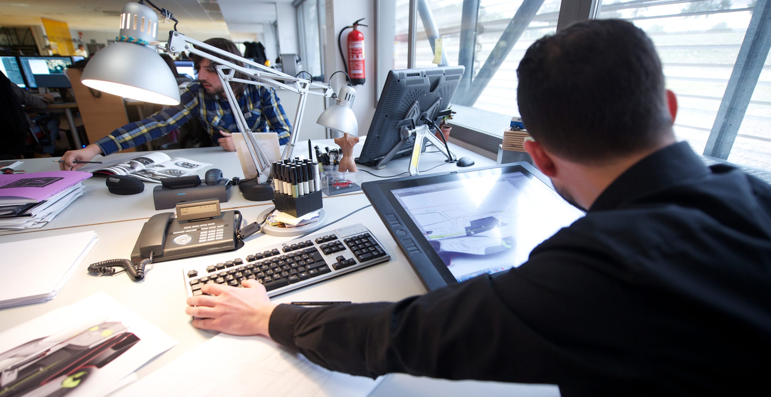 View behind a desk worker’s shoulder with a smart tablet on the desk – SEAT Human Resources