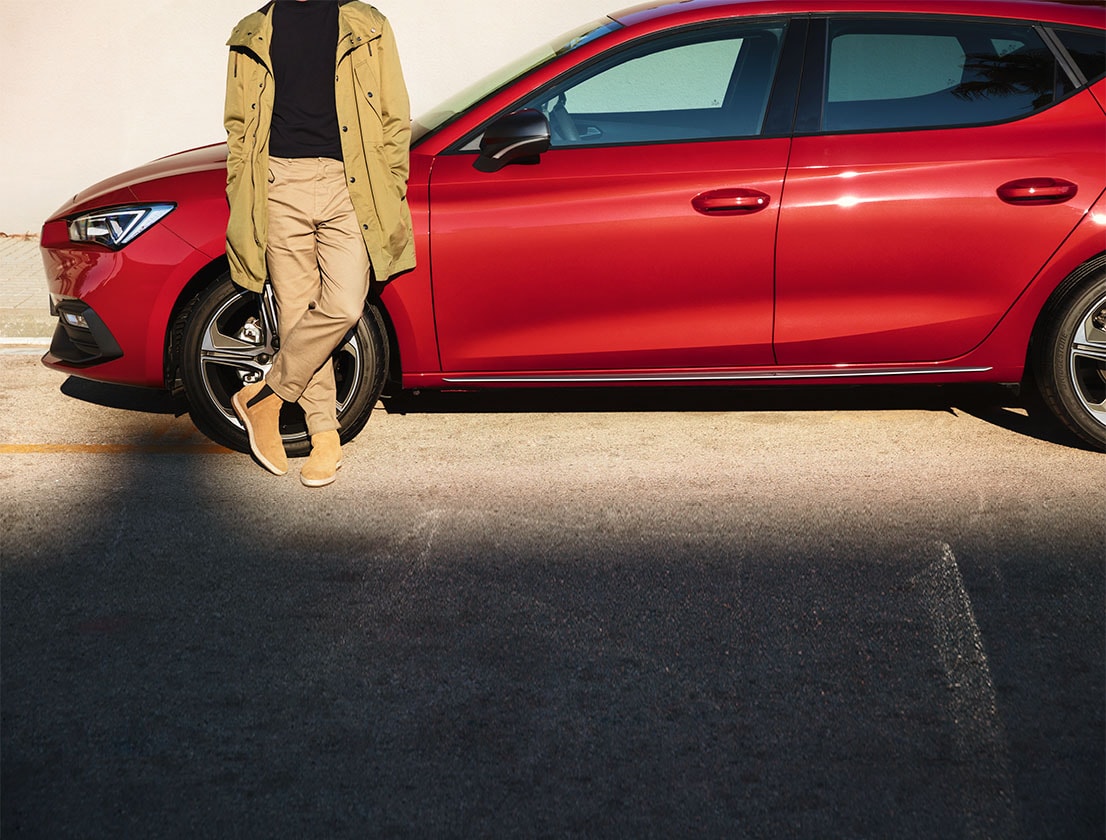 man standing next to seat leon sportstourer desire red colour